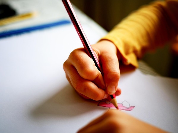 Kind tekent roze auto op wit papier